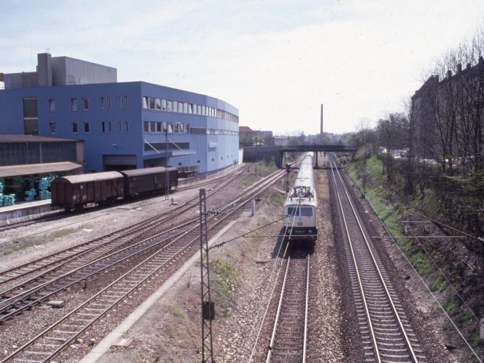 Zum Vergleich ein Foto aus den 80er Jahren vom gleichen Ort aus: Die Strecke München Augsburg war nur zweigleisig und gehörte damals noch nicht zum Augsburger Hbf. Links im Bild die alten Ladehöfe, mit dem Gleisanschluss der Fa. Attinger und dem Gleis zur Augsburger Lokalbahn. Quelle Stadtarchiv Augsburg.